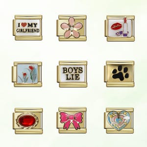 May include: Nine gold-toned charm bracelets with various designs. The charms include a flower, lipstick and lips, a paw print, a red gem, a pink bow, a heart, and text that reads "I MY GIRLFRIEND" and "BOYS LIE".