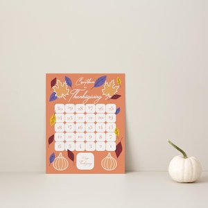 May include: A rectangular Thanksgiving countdown calendar printed on an orange background with white numbered squares from 1 to 30. The design features colorful autumn leaves, two line-art pumpkins, and the text Countdown to Thanksgiving.