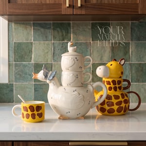 May include: A charming tea set with a duck-shaped teapot and stacked cups, alongside a giraffe-shaped tea set. A yellow mug with brown spots and a spoon are also present. The background features the text "YOUR MATCHA FINDS".