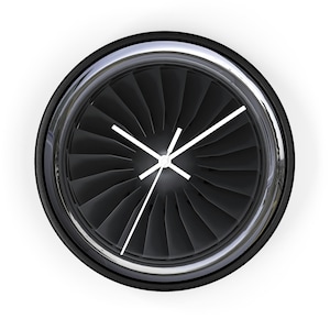 May include: A round wall clock featuring a jet engine design. The clock face is black with silver-colored blades and white hands. The clock has a black bezel with a silver-colored trim.