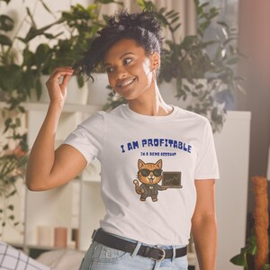 Może przedstawiać: Biały t-shirt z krótkim rękawem z grafiką przedstawiającą kota z kreskówki w garniturze i okularach przeciwsłonecznych, trzymającego laptopa. Tekst nad kotem brzmi I AM PROFITABLE IN A DEMO ACCOUNT niebieskimi literami z mniejszą czcionką poniżej.