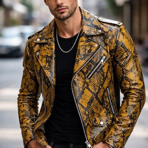 Può includere: Giacca in pelle con motivo a pelle di serpente gialla e nera con chiusura a zip argentata e camicia nera. La giacca ha un classico stile biker con colletto a revers e più tasche. La persona indossa una collana d'argento e jeans neri.