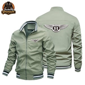 Può includere: Giacca bomber verde salvia con chiusura full-zip, colletto, polsini e orlo a righe bianche e nere. La giacca presenta un logo Bentley sul petto e sulla schiena. Il logo Jacket By Premium si trova in alto a sinistra.