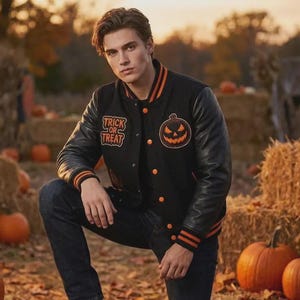 Può includere: Una giacca varsity nera con maniche nere, polsini a coste a righe arancioni e bottoni arancioni. Il petto presenta una toppa ricamata a forma di zucca arancione e la scritta Trick or Treat in arancione su sfondo nero.