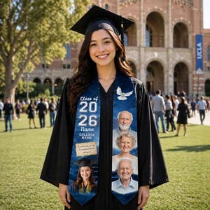 Op de afbeelding: Een lachende afgestudeerde in een zwarte toga en baret draagt een gepersonaliseerde afstudeer stropdas. De blauwe stropdas heeft de tekst "Class of 2026" en een fotocollage. Een witte duif staat ook op de stropdas.