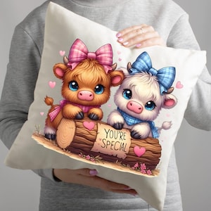 Pu&ograve; includere: Un cuscino decorativo con un'illustrazione di due mucche dei cartoni animati. Una &egrave; marrone, l'altra bianca, entrambe con fiocchi e sciarpe. Tengono un tronco con la scritta "YOU'RE SPECIAL". Sono presenti anche cuori e fiori rosa.