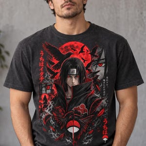 May include: A charcoal gray t-shirt featuring a graphic print of an anime character with red eyes, black hair, and a headband. The design includes a large red moon, black crows, smoke, and the Uchiha clan symbol, with Japanese text integrated throughout.
