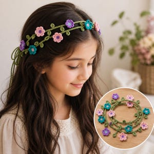 Peut inclure: Un serre-tête floral au crochet avec des fleurs roses, violettes et turquoise et des feuilles vertes. Le serre-tête est présenté sur une jeune personne aux longs cheveux bruns. Un accessoire délicat et fait à la main.