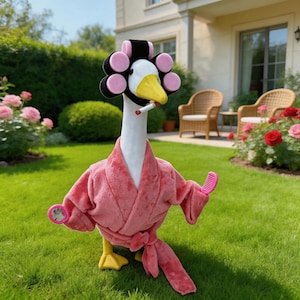 May include: A plush goose wearing pink hair rollers, a pink robe, and holding a comb. The goose has a cigarette in its beak and is standing on green grass in front of a house and rose bushes.
