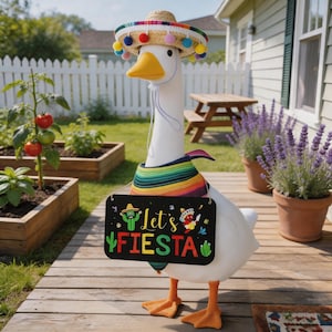 May include: A white goose figurine wearing a sombrero, a colorful poncho, and holding a sign that says "Let's Fiesta." The goose has orange feet and a yellow beak. The background includes a garden with tomato plants and lavender.