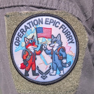 May include: Embroidered patch with the text "OPERATION EPIC FURRY." The patch features a cartoon fox and wolf giving a high-five, with an American flag and a world map in the background. The patch is circular with a black border.