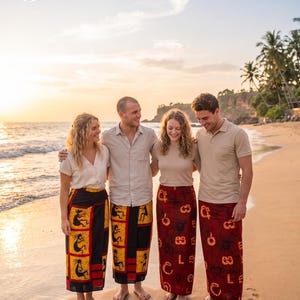 May include: Four individuals wearing beige tops and patterned batik sarongs. Two sarongs feature black and yellow panels with stylized figures, while the other two are deep red with dark circular and linear motifs. The logo reads Lady & Gents Modern Batik.