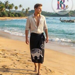 May include: A beige button-down shirt with long sleeves and a black sarong featuring a white elephant batik print. The sarong is tied at the waist. The image includes the text LADY & GENTS MODERN BATIK, Sri Lankan Handmade Batik Sarong, and Material-Cotton.