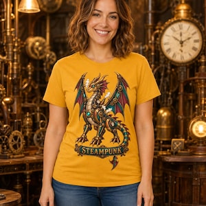 Op de afbeelding: Een mosterdgeel T-shirt met korte mouwen en een grafische illustratie van een mechanische draak met metalen vleugels en tandwielen. Onder de draak staat een decoratieve banner met de tekst STEAMPUNK in donkerblauwe en gouden letters.