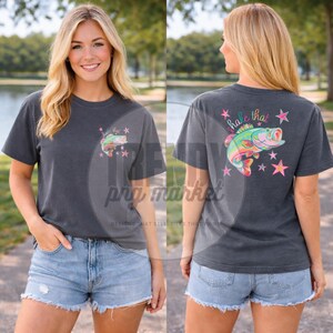 Pu&ograve; includere: T-shirt grigio scuro con una grafica di pesce colorata e la scritta "hale that". La grafica include un pesce con accenti rosa, verdi e gialli, circondato da stelle rosa e arancioni. La maglietta &egrave; a maniche corte.