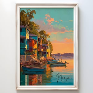 Può includere: Stampa artistica incorniciata di una scena costiera con edifici colorati e barche sull'acqua. L'opera presenta un tramonto vibrante con sfumature di arancione, blu e verde acqua. La parola "Noosa" è scritta in corsivo.