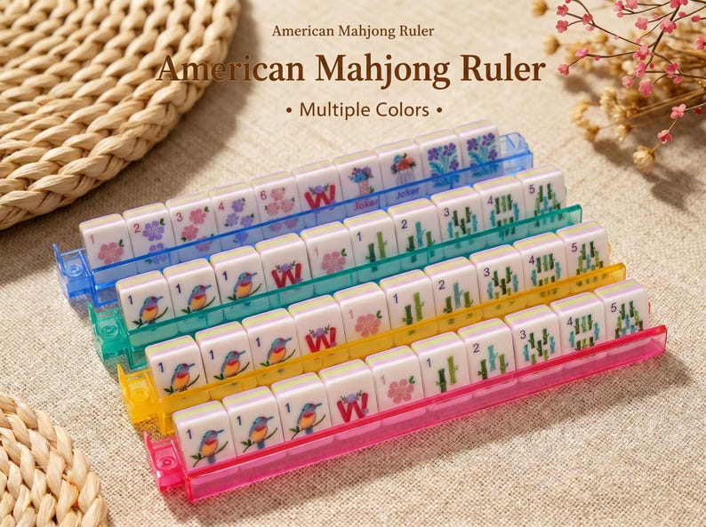 May include: A set of four American Mahjong rulers in blue, green, yellow, and pink, each holding a row of white tiles featuring colorful bird, flower, bamboo, and letter graphics. The text American Mahjong Ruler is printed above the items.