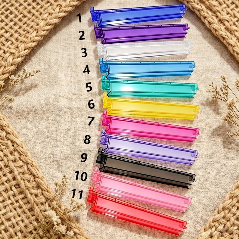 May include: A set of eleven plastic bag sealing clips in various translucent colors including blue, purple, clear, light blue, teal, yellow, pink, lavender, black, light pink, and red, each labeled with a black number from one to eleven.