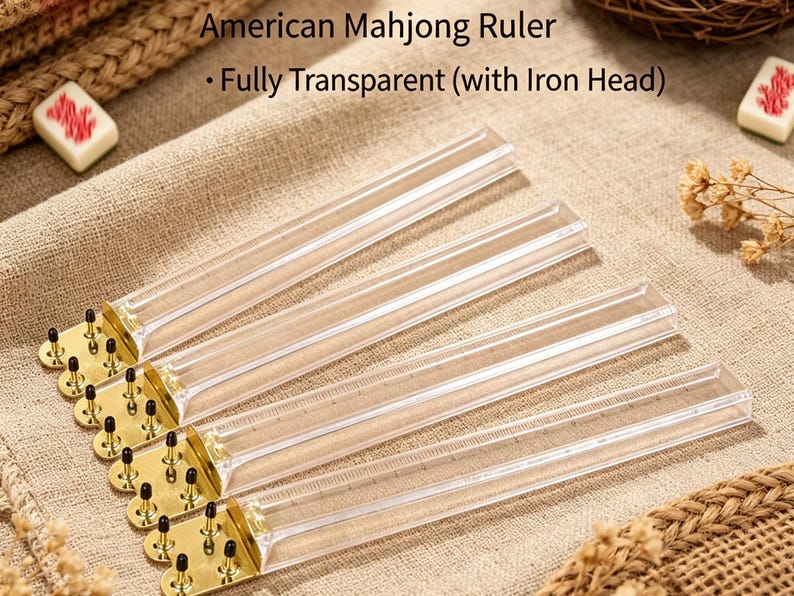 May include: Four American Mahjong rulers made of clear, transparent plastic. Each ruler features a gold-toned metal end piece with four small, black-tipped metal pins. The text "American Mahjong Ruler - Fully Transparent (with Iron Head)" is visible.