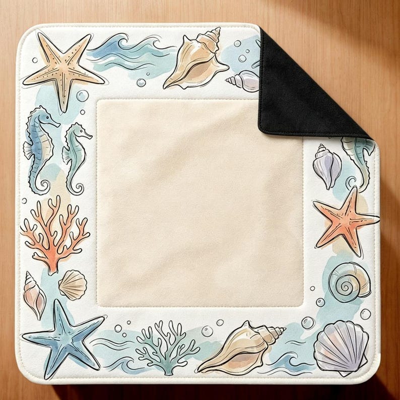 Peut inclure: Un tapis carr&eacute; avec un centre cr&egrave;me et une bordure orn&eacute;e d'illustrations &agrave; l'aquarelle repr&eacute;sentant des &eacute;toiles de mer, des hippocampes, divers coquillages, du corail et des vagues bleues. Le coin sup&eacute;rieur droit est repli&eacute; sur un envers noir.
