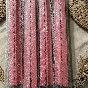 May include: Four long, narrow, pink strips with a scalloped edge on one side, each individually encased in clear bubble wrap packaging. The strips are arranged vertically and parallel to each other, displaying a consistent matte pink color.