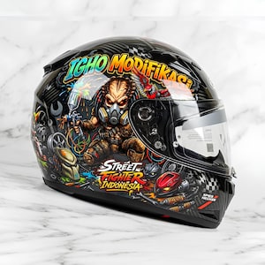 May include: A black motorcycle helmet featuring a vibrant graphic design of a creature wearing a gas mask and holding a spray paint gun. The text IGHO MODIFIKASI and STREET FIGHTER INDONESIA is printed in colorful, stylized lettering across the side.