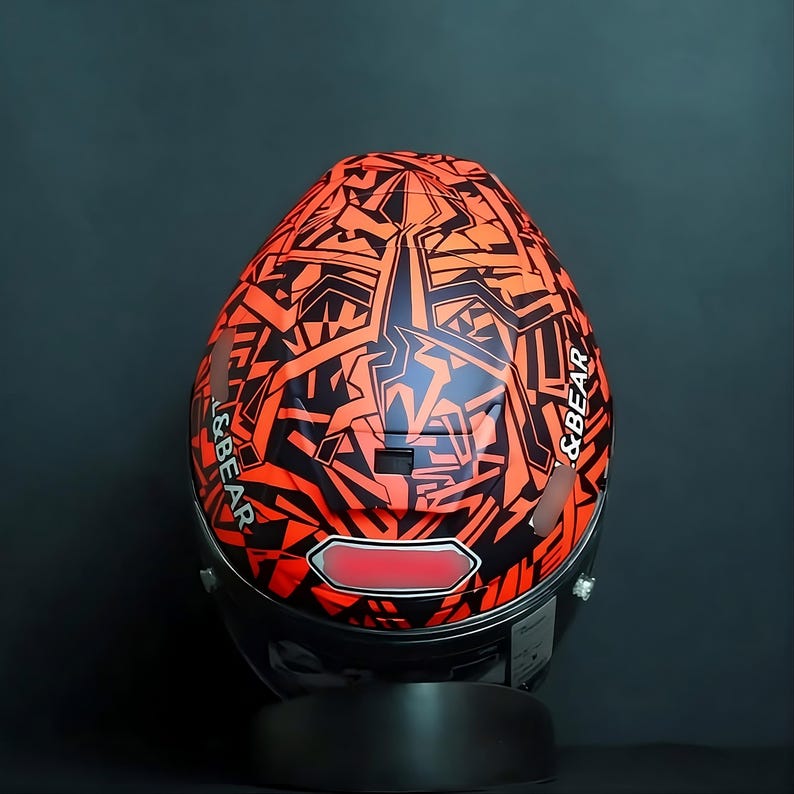 Detailed macro shot of the iconic Marc Marquez "Ant" logo custom airbrushed on a Shoei X-15 helmet. Vibrant red and black motifs with 3D airbrush shading. Superior finishing using Spies Hecker clear coat for a mirror-like shine. Bespoke motorsport helmet design for Marc Marquez fans and superbike riders. High-performance Shoei X-Fifteen AIM+ shell technology customized for a unique, one-of-a-kind luxury collector's item.