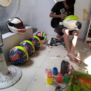 Behind the scenes at Igho Modifikasi Indonesia workshop.
Professional airbrush artist hand-painting a custom motorcycle helmet.
Showcasing authentic craftsmanship and bespoke design process automotive since 2012.