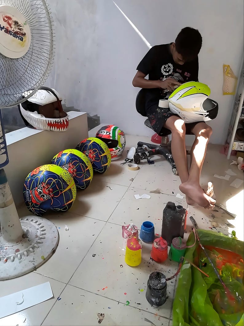 Behind the scenes at Igho Modifikasi Indonesia workshop.
Professional airbrush artist hand-painting a custom motorcycle helmet.
Showcasing authentic craftsmanship and bespoke design process automotive since 2012.
