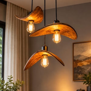 May include: A three-light pendant chandelier featuring curved, natural wood grain shades suspended from a circular black ceiling canopy by black cords. Each light fixture holds a single exposed Edison-style light bulb, casting a warm glow.