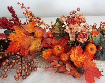 Könnte beinhalten: Ein Herbst-Mittelstück mit orangefarbenen, roten und braunen Blättern, kleinen Kürbissen und Beeren. Das Mittelstück befindet sich auf einer weißen Tischdecke mit einem Jute-Läufer.