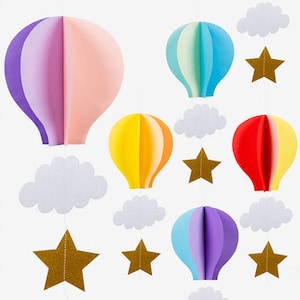 Könnte beinhalten: Ein Set aus bunten Papier-Heißluftballons, Wolken und goldenen Sternen, die an Schnüren hängen. Die Ballons sind in Schattierungen von Rosa, Blau, Gelb und Lila geschichtet. Die Wolken sind weiß und die Sterne sind golden.