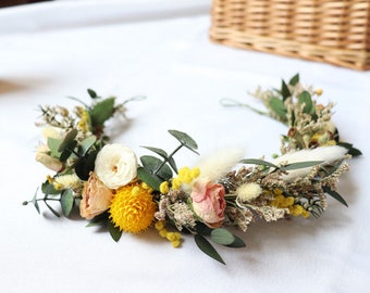 May include: A floral crown made with dried flowers, including white roses, pink roses, yellow mimosa, and eucalyptus leaves.