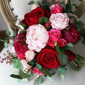 May include: A bridal bouquet with pink and red roses, peonies, and greenery.