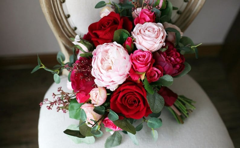 May include: A bridal bouquet with pink and red roses, peonies, and greenery.