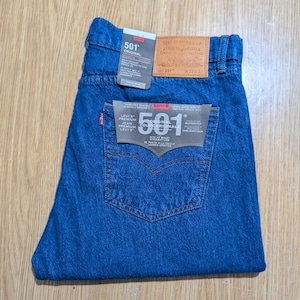 Può includere: Jeans blu in denim con l'etichetta "501 ORIGINAL". I jeans hanno un classico design a cinque tasche e un'etichetta rossa Levi's. La vita è W38 e la lunghezza è L32.