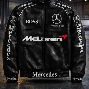Può includere: Giacca in pelle nera con dettagli e loghi bianchi. Presenta i marchi "BOSS", "Mercedes-Benz" e "McLaren". La giacca ha "Mercedes" stampato sulle maniche e sull'orlo, e "Bridgestone" sul colletto.