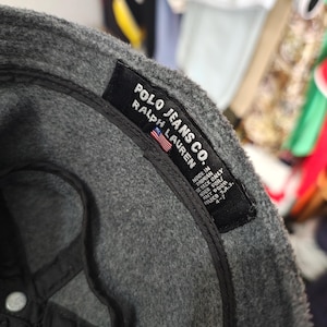 May include: A gray Polo Jeans Co. baseball cap with a black interior. The label reads "POLO JEANS CO. RALPH LAUREN" with a small American flag. The cap is made in Taiwan.