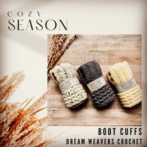 May include: Three rolled crochet boot cuffs in cream, gray, and light yellow, each with a button detail. The image includes the text "Cozy Season", "Boot Cuffs", and "Dream Weavers Crochet". The cuffs are displayed on a wooden surface.