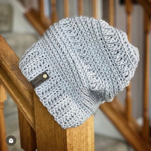 May include: Gray crocheted beanie with a leather patch that reads "Dream Believe Conquer".