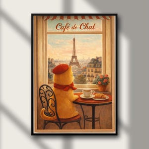 May include: A framed print of a cat at a Parisian cafe. The cat, wearing a red beret and scarf, sits at a table with coffee and a croissant, gazing at the Eiffel Tower. The print is titled "Café de Chat".