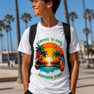 Peut inclure: T-shirt blanc avec un motif coloré de coucher de soleil, de palmiers et d'une planche de surf. Le texte "SCHOOL IS OUT SUMMER TIME" est imprimé sur le devant. Le t-shirt est porté par une personne avec un sac à dos, à l'extérieur par une journée ensoleillée.