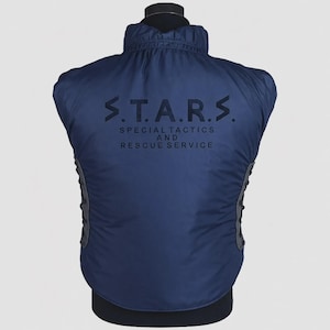 Op de afbeelding: Marineblauwe vest met de tekst "S.T.A.R.S. SPECIAL TACTICS AND RESCUE SERVICE" op de rug. De vest heeft een hoge kraag en getextureerde zijpanelen. Gepresenteerd op een zwarte mannequin. Praktisch kledingstuk.