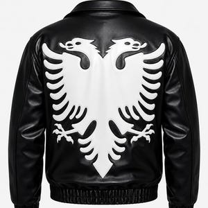 May include: A black leather jacket featuring a large, white, embossed double-headed eagle emblem on the back. The jacket has a classic collar, long sleeves with ribbed cuffs, and a ribbed hem, showcasing a smooth, matte finish throughout the design.