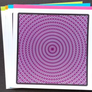 May include: A stack of square greeting cards with a purple and white geometric design. The design features a concentric pattern of diamond shapes. The cards have a black border and are stacked with pink, blue, yellow, and orange cardstock.