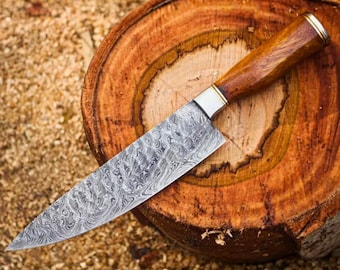 May include: A Damascus steel chef's knife with a wooden handle and a silver bolster. The blade has a unique swirling pattern. The knife rests on a round, wooden cutting board, showcasing the blade's design and craftsmanship.