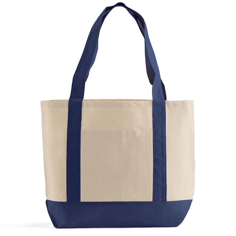 Puede incluir: Un bolso tote de lona color crema con asas y detalles en azul marino. El bolso tiene una base azul marino y un bolsillo frontal. Este bolso reutilizable es adecuado para llevar comestibles o art&iacute;culos personales.
