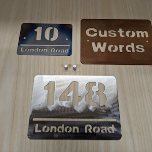 May include: Three metal house number signs with cut-out numbers and text. One sign is blue with the number 10 and "London Road". Another is brown with "Custom Words". The third is silver with 148 and "London Road". Two silver screws are visible.