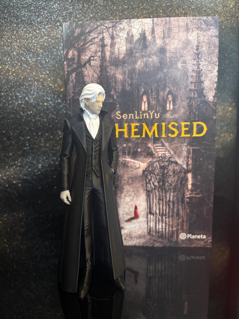 Puede incluir: Una figura de un personaje con cabello blanco que viste un abrigo largo negro, un chaleco negro y una corbata blanca, frente a la portada de un libro titulada SenLinYu THEMISED con la ilustraci&oacute;n de un castillo oscuro y una peque&ntilde;a figura roja.