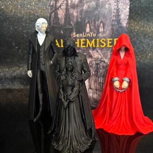 Puede incluir: Tres figuras de pie frente a la portada de un libro titulada SenLinYu ALHEMISED. A la izquierda, una figura con abrigo negro y pelo blanco. En el centro, una figura negra de dos personas abrazadas. A la derecha, una figura con capa roja.